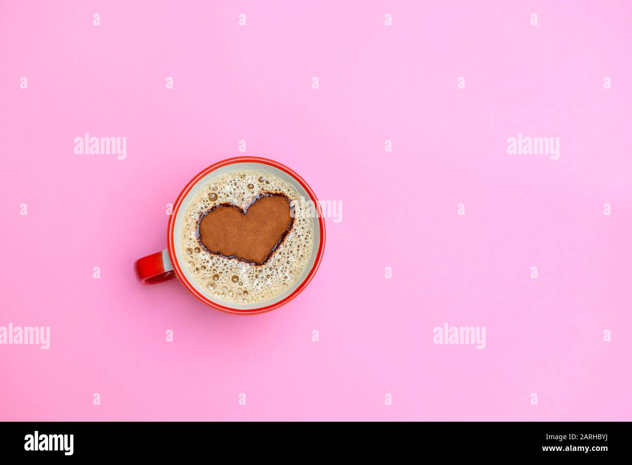 Tazza di cappuccino con forma a cuore su morbido fondo rosa. Buon concetto di mattina. Immagine con spazio di copia, vista dall'alto Foto Stock