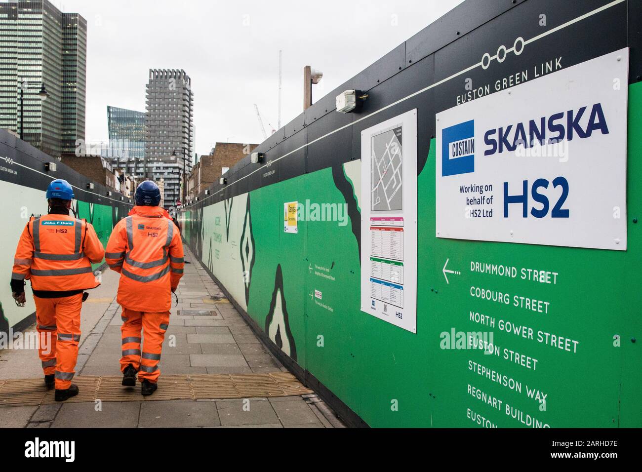 Londra, Regno Unito. 28 Gennaio 2020. Gli operai edili che indossano giacche HS2 passano un cartello indicante un sito designato per il progetto HS2 vicino alla stazione di Euston. Le proiezioni dei costi per il progetto sono state riportate per essere aumentate a £106bn e il governo dovrebbe prendere una decisione per quanto riguarda la sua vitalità questa settimana. Credit: Mark Kerrison/Alamy Live News Foto Stock