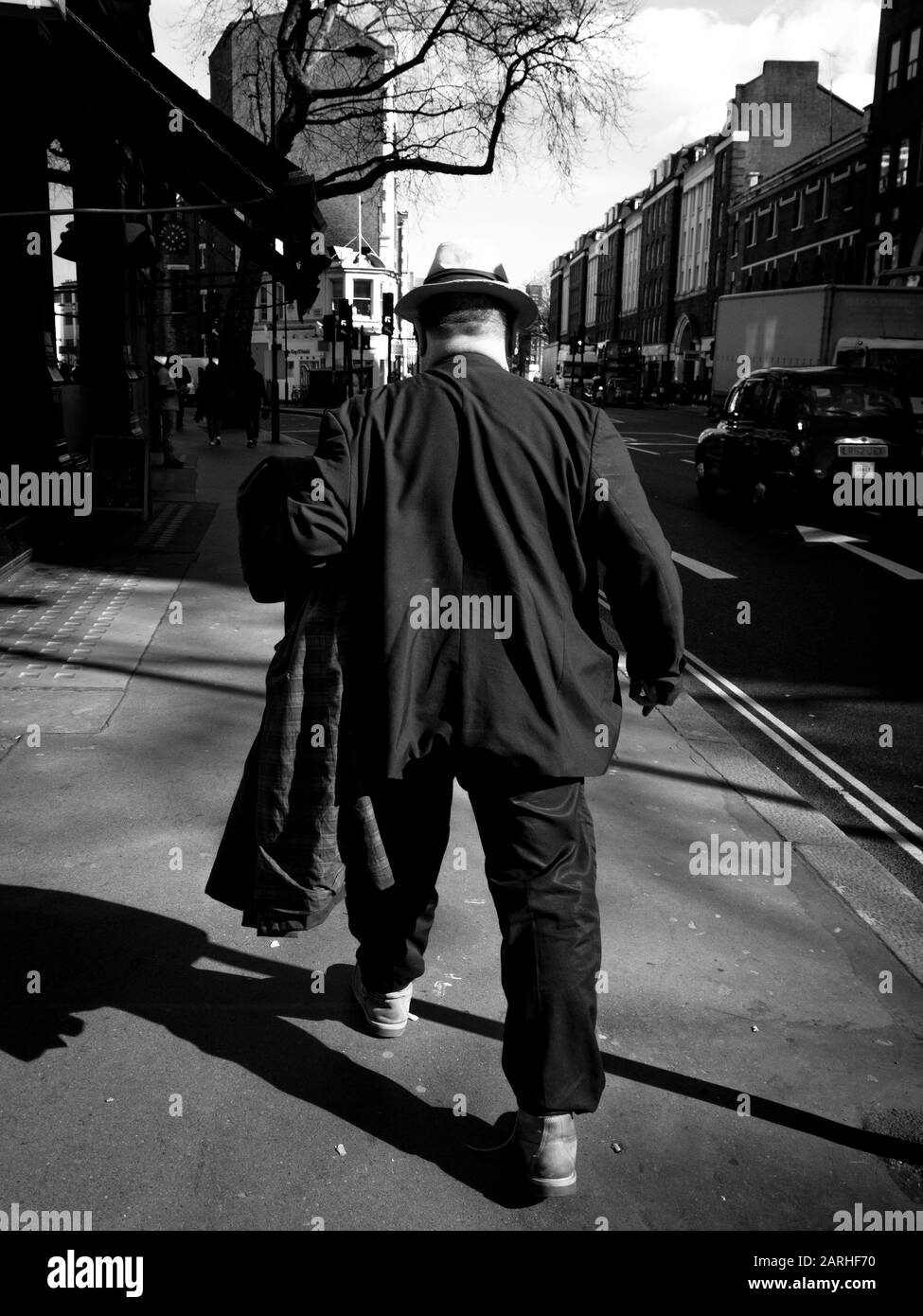 Uomo grande in una tuta grande cammina lungo una strada di Londra Foto Stock