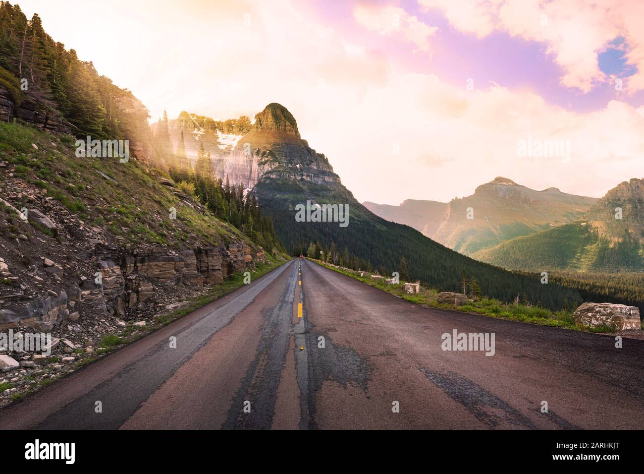 Bellissima strada diritta in Montana con raggi di sole di mattina presto che splendono attraverso le montagne sulla strada avanti Foto Stock