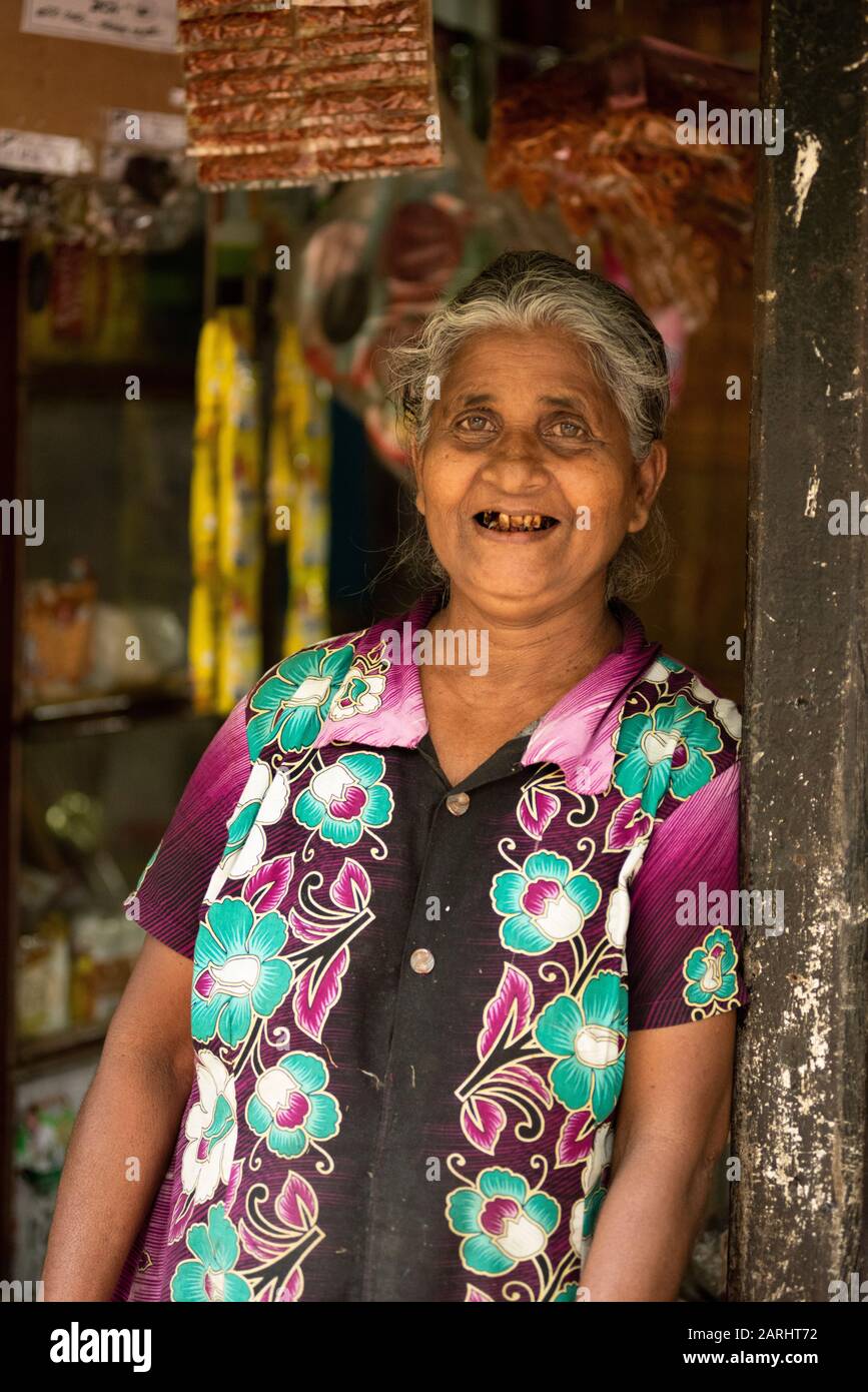 Negozio di donna locale, alla porta del negozio, provincia di Sabaragamuwa, vicino alla Riserva forestale di Sinharaja, Sri Lanka Foto Stock