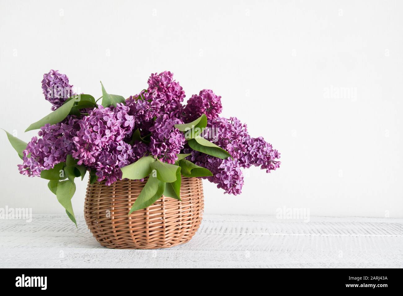 Cesto di fiori lilla su tavola bianca in legno. Madri e donne giorno. Orientamento orizzontale. Foto Stock