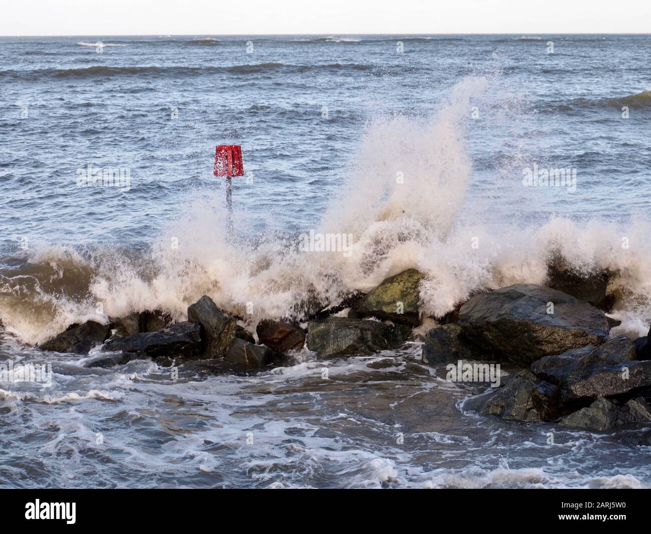 Onde che si infrangono su rocce, segnalino rosso, Galles Foto Stock