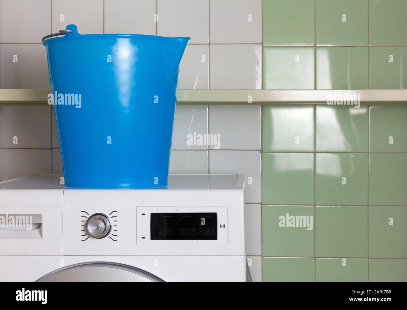 Secchio blu sulla parte superiore di una lavatrice in una lavanderia Foto Stock