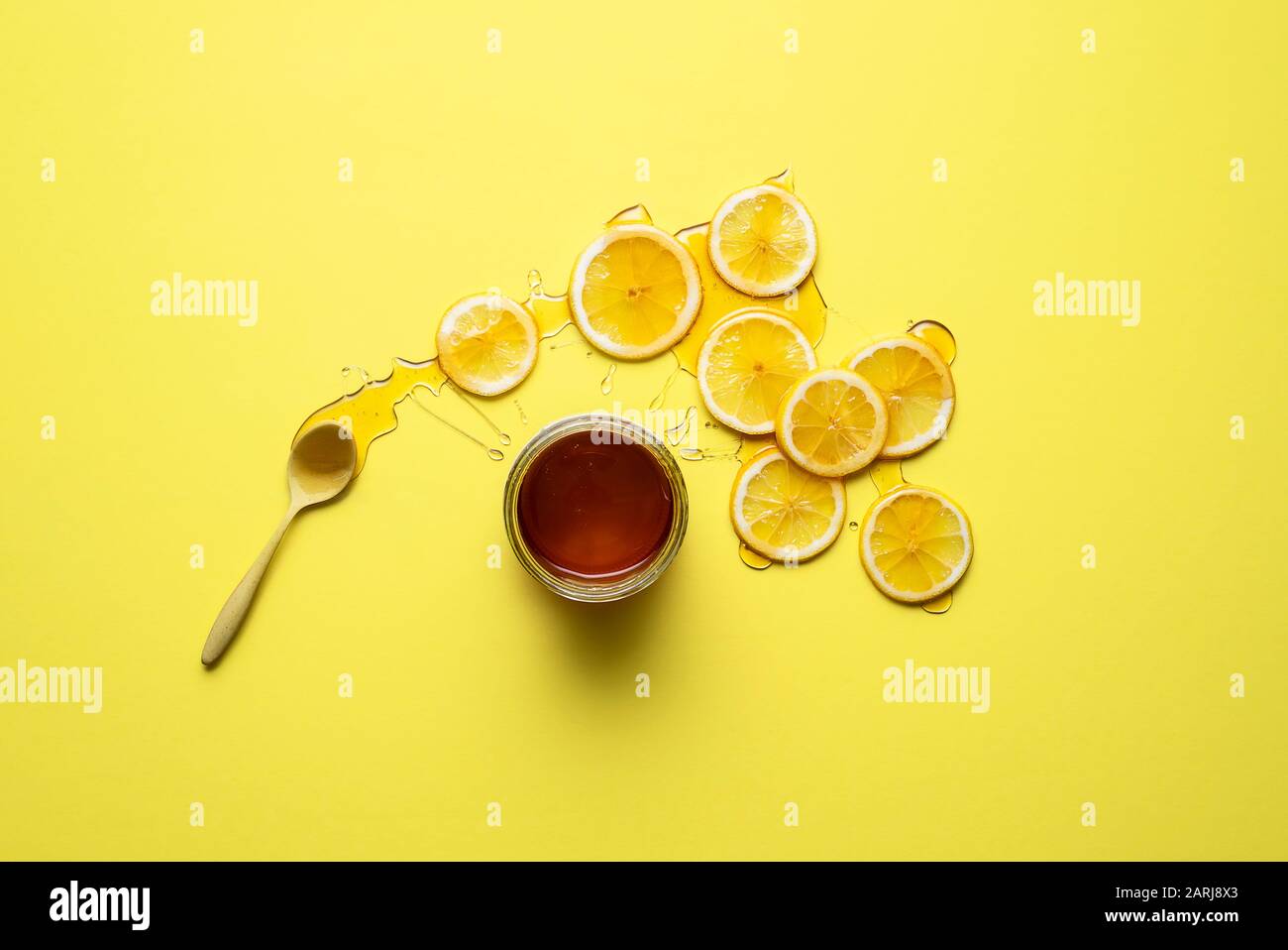 Vaso di miele e fette di limone con miele su di loro, su sfondo giallo. Piatto di limoni e miele. Rimedio freddo naturale. Trattamento di detox e immunità. Foto Stock