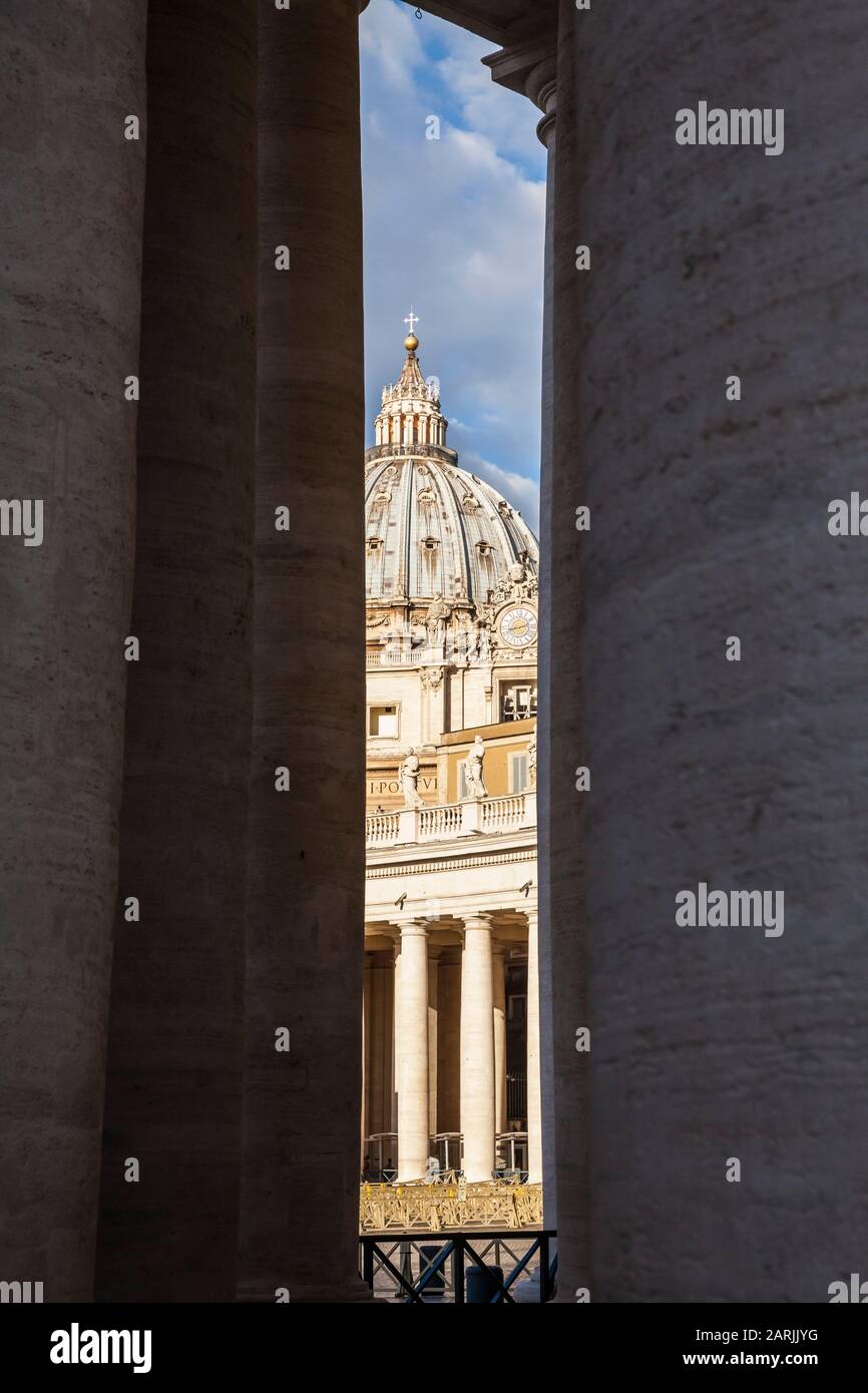 Una vista della Basilica di San Pietro tra le colonne del colonnato intorno a Piazza San Pietro, Città del Vaticano. Foto Stock