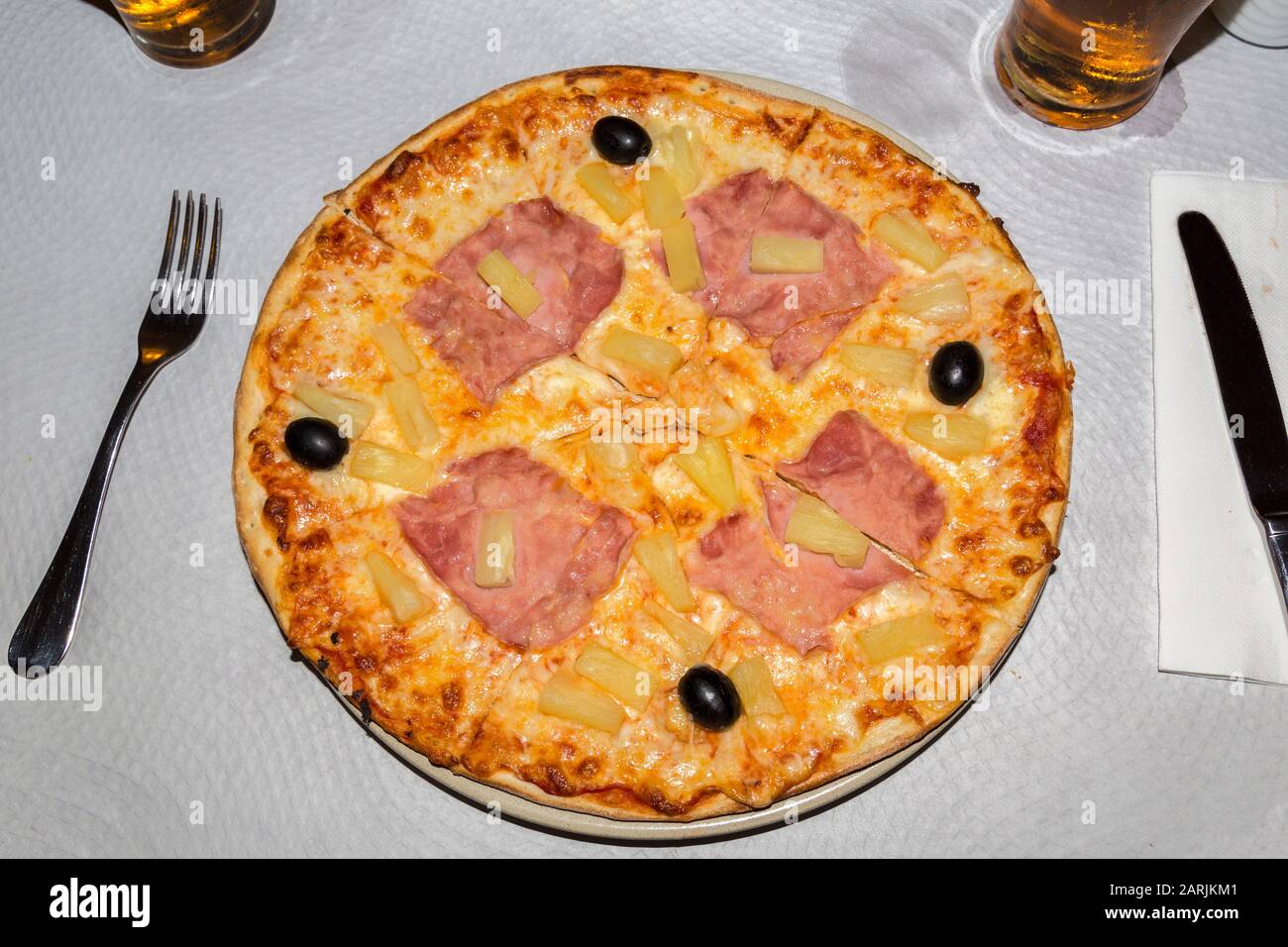 Prosciutto, ananas e pizza d'oliva serviti su tovaglia usa e getta, Algarve, Portogallo Foto Stock