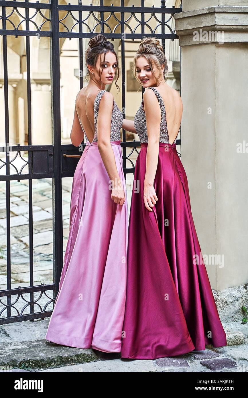 Due belle sposini ragazze bionde e donne brunette indossando elegante viola viola lilla lavanda raso raso abito da sposa con Foto Stock