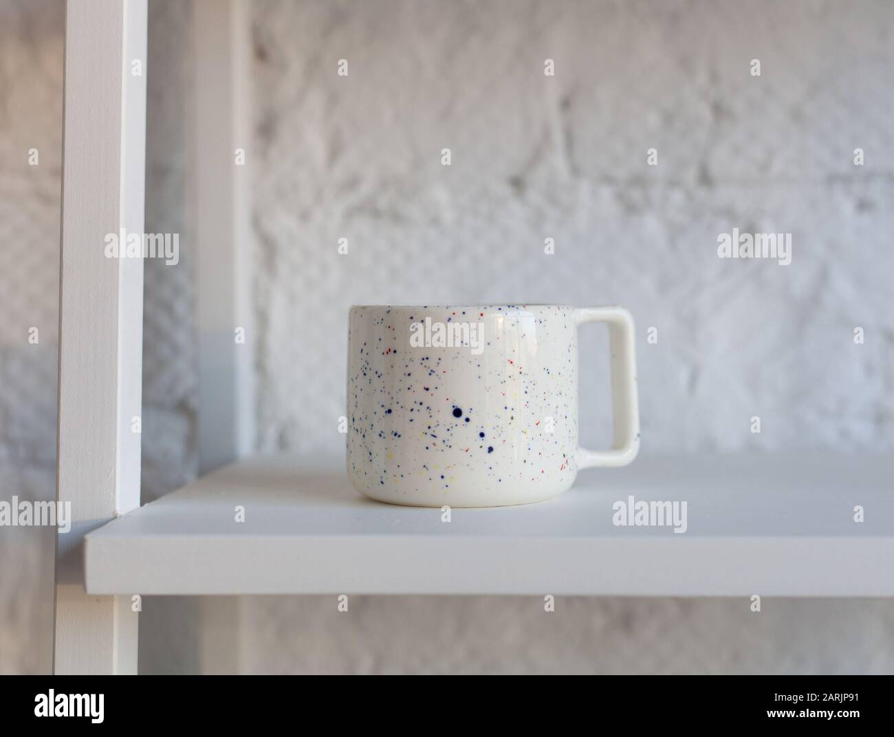 Bella tazza di ceramica fatta a mano su libreria bianca Foto Stock