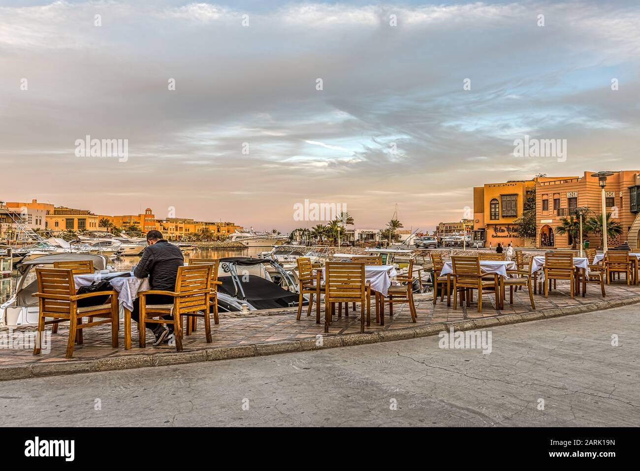 Ristorante con un uomo seduto a un tavolo al tramonto presso la Marina di Abu Tig a el Gouna, Egitto, 12 gennaio 2020 Foto Stock