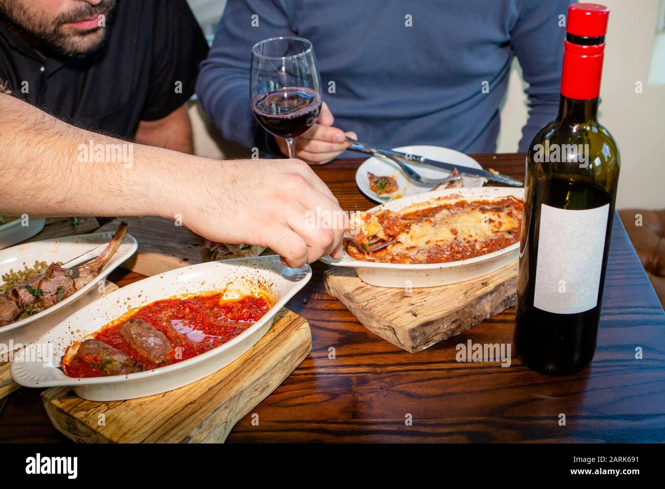 Vista ravvicinata di due uomini che condividono un pasto con una bottiglia di vino Foto Stock