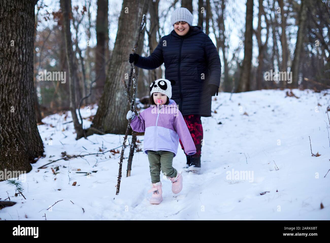 Escursione per mamma e bambino su un sentiero forestale innevato. Foto Stock