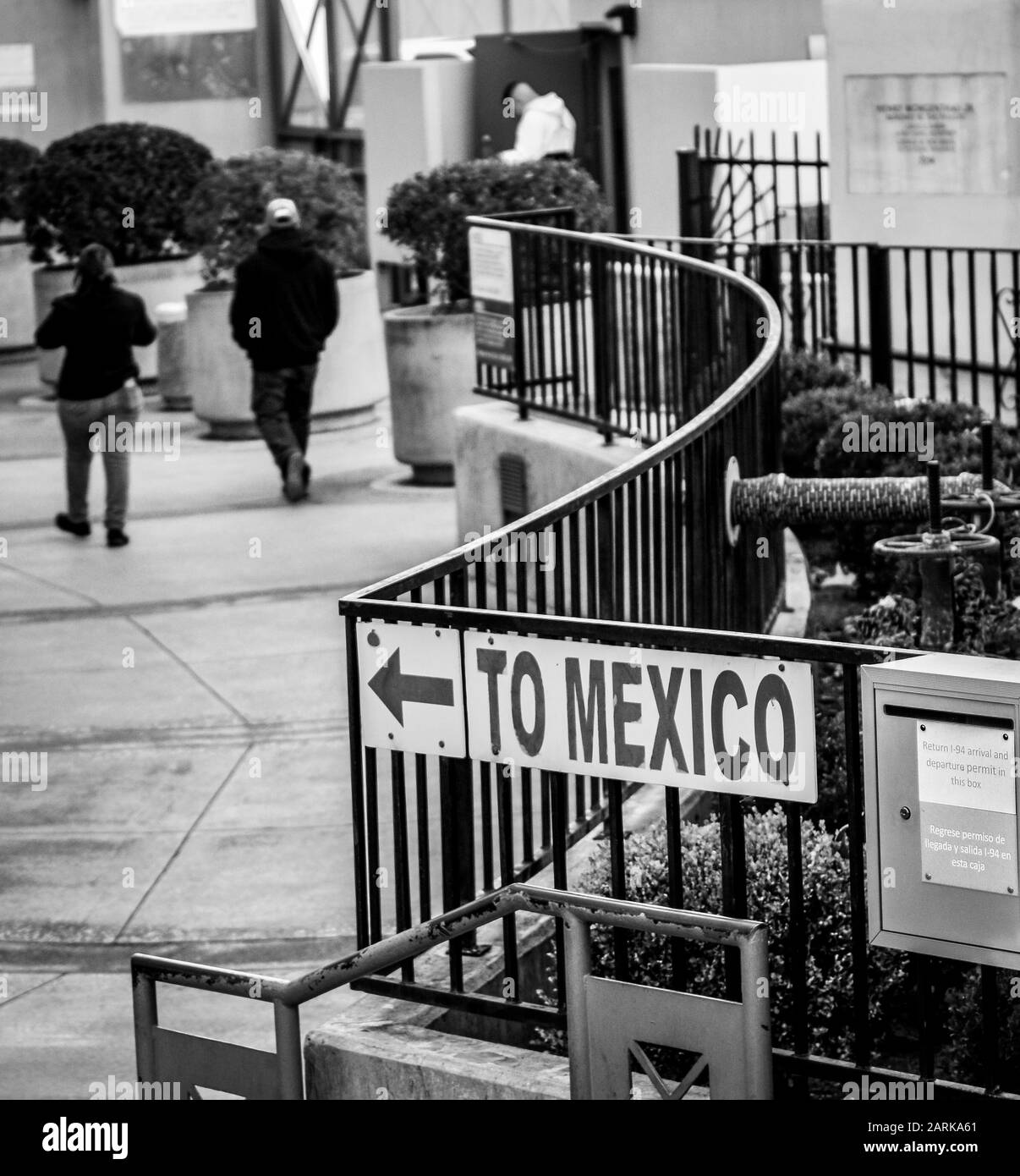 Un cartello che indica il Messico, con vista posteriore delle persone che camminano verso il confine USA-Messico in un punto di check-in a Nogales, AZ, USA, in bianco e nero Foto Stock