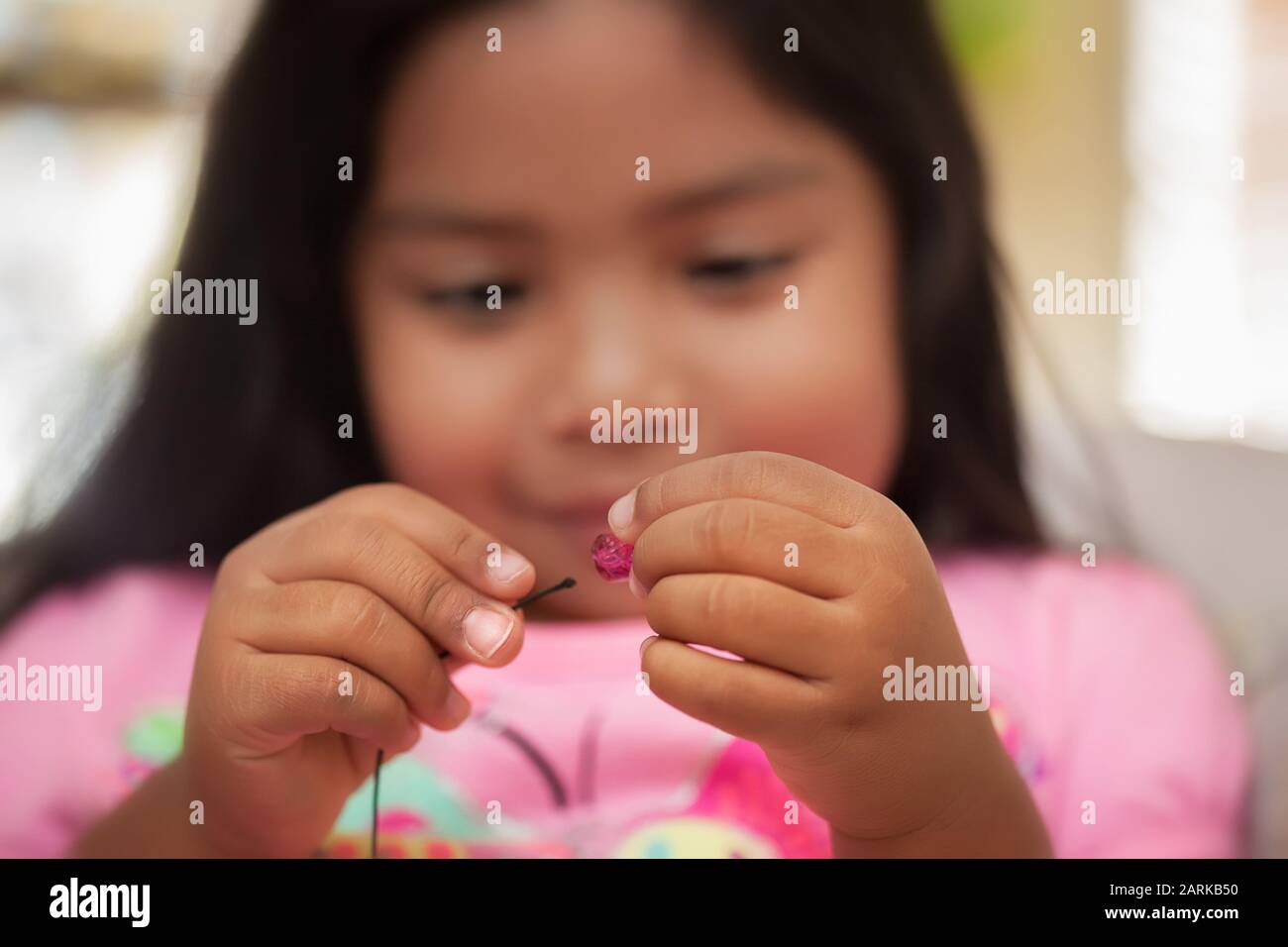 Un bambino che migliora le capacità motorie utilizzando una presa a pinza mentre tiene corda e perline. Foto Stock