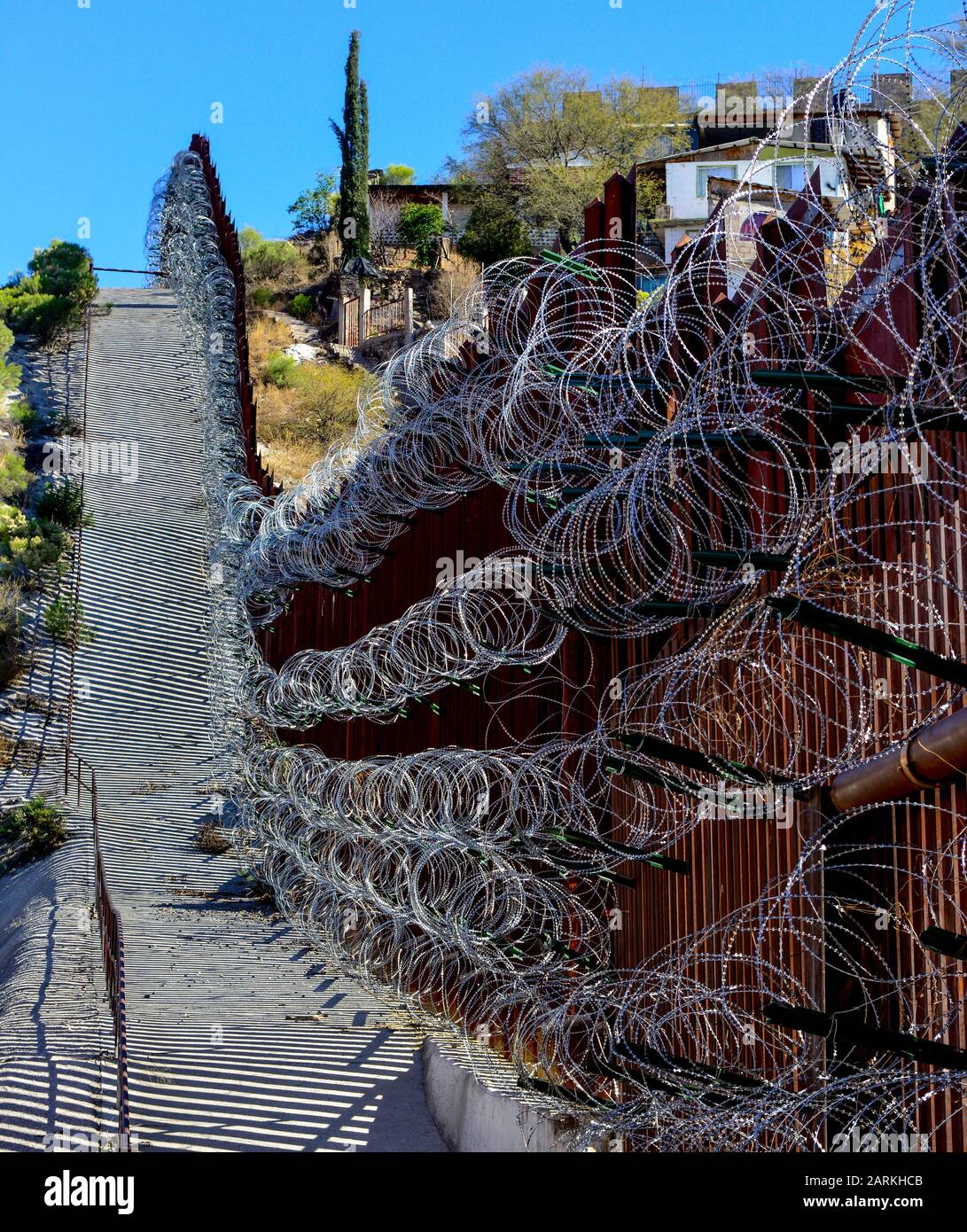 Vista del confine internazionale USA/Messico con filo di rasoio in salita con le case messicane sull'altro lato del recinto da Nogales, AZ, USA Foto Stock