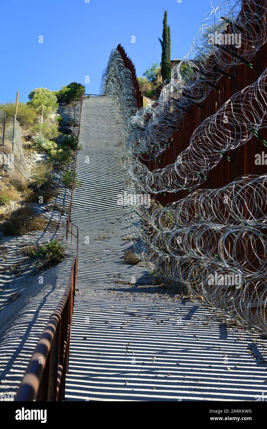 Vista del confine internazionale USA/Messico con filo di rasoio in salita con il Messico dall'altro lato del recinto da Nogales, AZ, USA Foto Stock