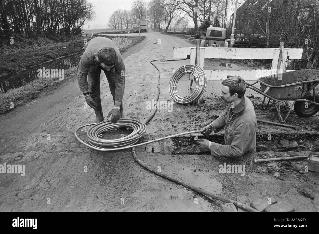 Sostituzione tubi acqua PVC con tubi di rame dopo aver trovato veleno nell'acqua potabile in Broek in Waterland Data: 28 gennaio 1981 luogo: Broek in Waterland, Noord-Holland Parole Chiave: Lavoratori, utensili, rame, tubo acqua Foto Stock