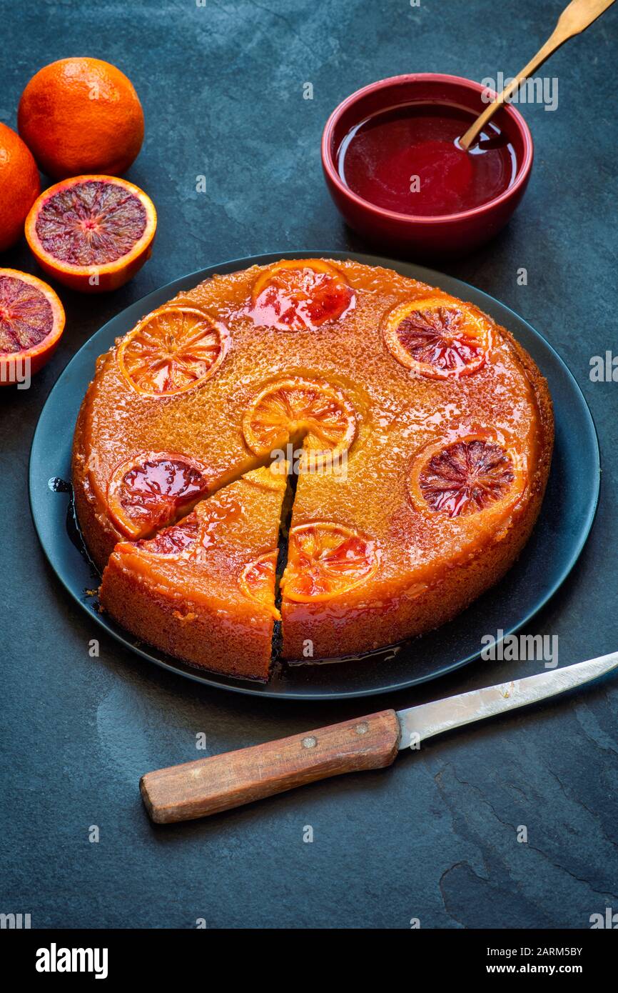 Torta di arance di sangue fatta in casa capovolta con sciroppo d'arancia di sangue su uno sfondo di ardesia Foto Stock