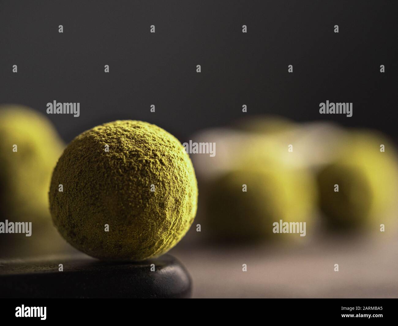 Tartufo fatto in casa caramella rivestita matcha tè polvere su sfondo scuro. Copiare lo spazio a destra per testo o disegno, banner. Profondità di campo bassa Foto Stock