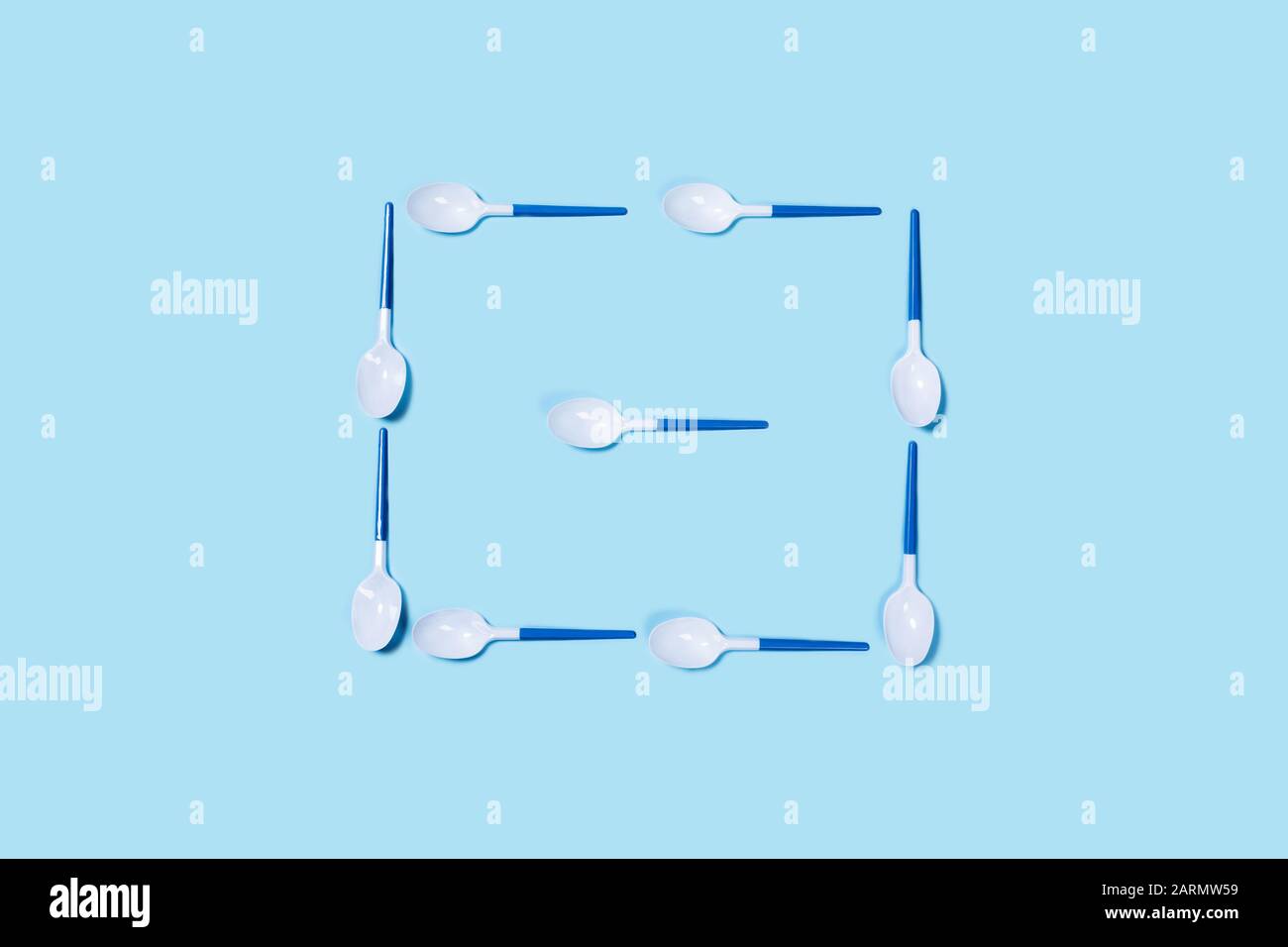 Immagine di cucchiai di plastica bianca su sfondo blu. Disposizione piatta, vista dall'alto. Disposizione piatta, vista dall'alto, spazio di copia. Foto Stock