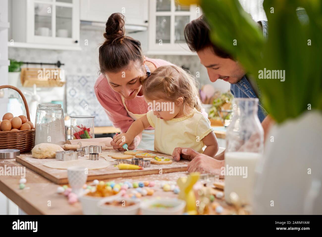 I genitori con i biscotti di decorazione del bambino per Pasqua Foto Stock