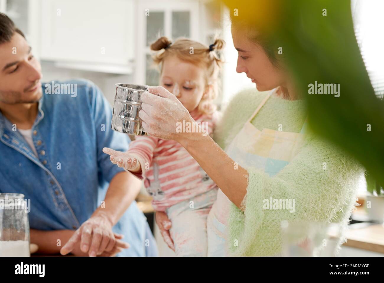 Genitori che insegnano a figlia come cuocere Foto Stock