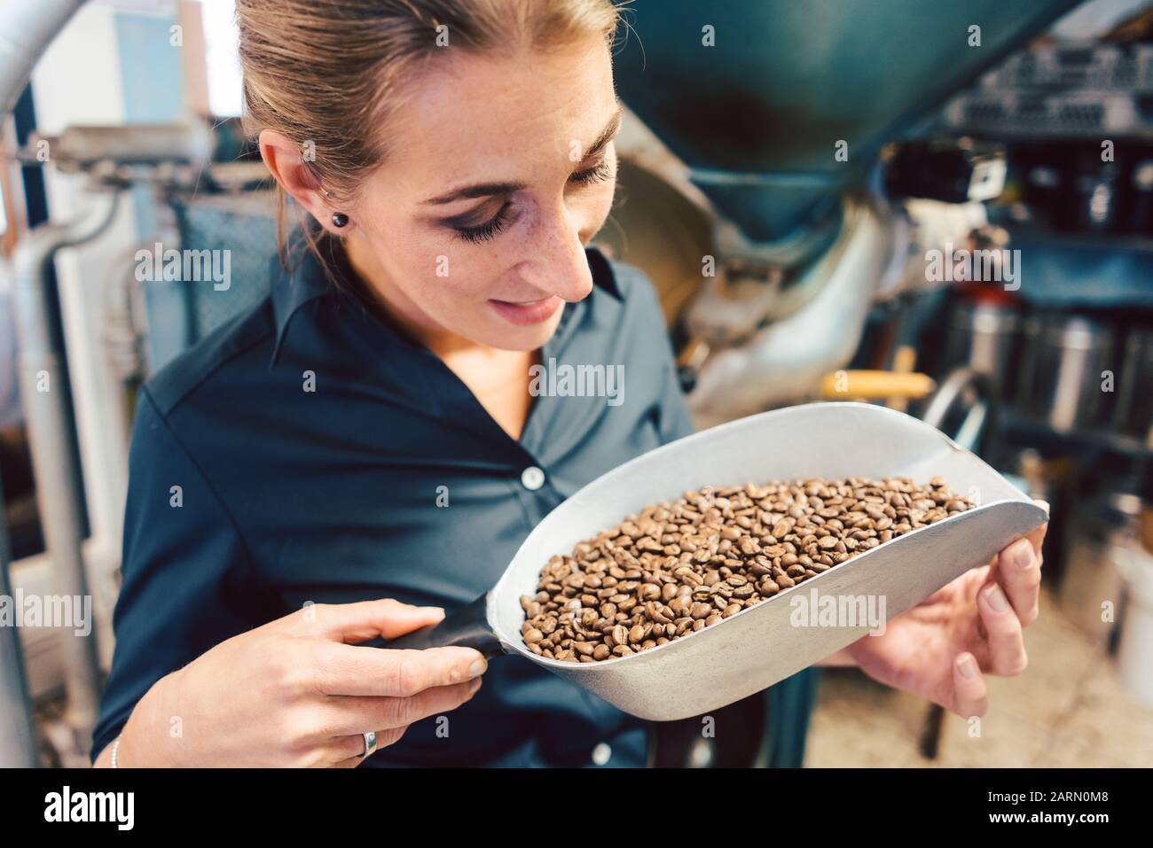 Donna in coffee roastery con chicchi freschi Foto Stock
