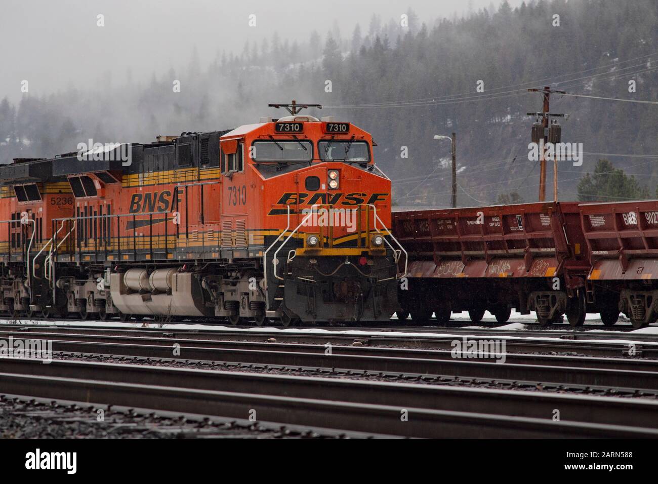 Una locomotiva BNSF nera, gialla e arancione, che gira al minimo sulle piste nella città di Troy, Montana. Burlington Northern e Santa Fe Railway sono stati formati in Foto Stock