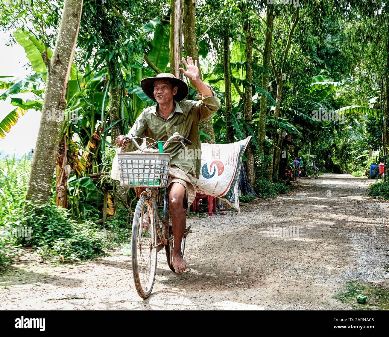 Duro lavoro contadino vietnamita in bicicletta. Gli agricoltori sono poveri di ricchezza materiale e ricchi di forza spirituale. Sempre un'espressione allegra. Foto Stock