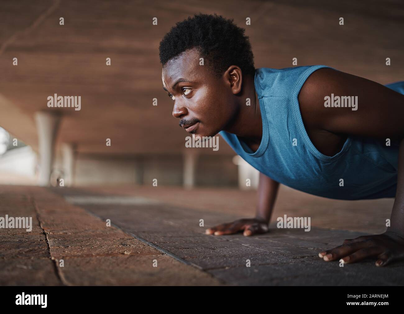 Giovane africano americano sport fisico uomo fare spinta-up sul marciapiede all'aperto Foto Stock