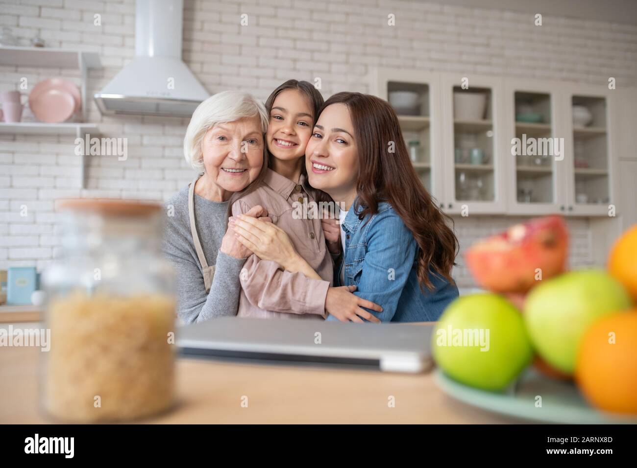 Giovane donna, anziana donna e bambina si abbracciarono sorridendo. Foto Stock