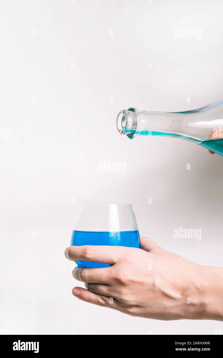 Bottiglia di champagne con liquido blu su sfondo bianco. Bevanda alcolica o analcolica. Alcolismo o concetto di partito. Foto Stock