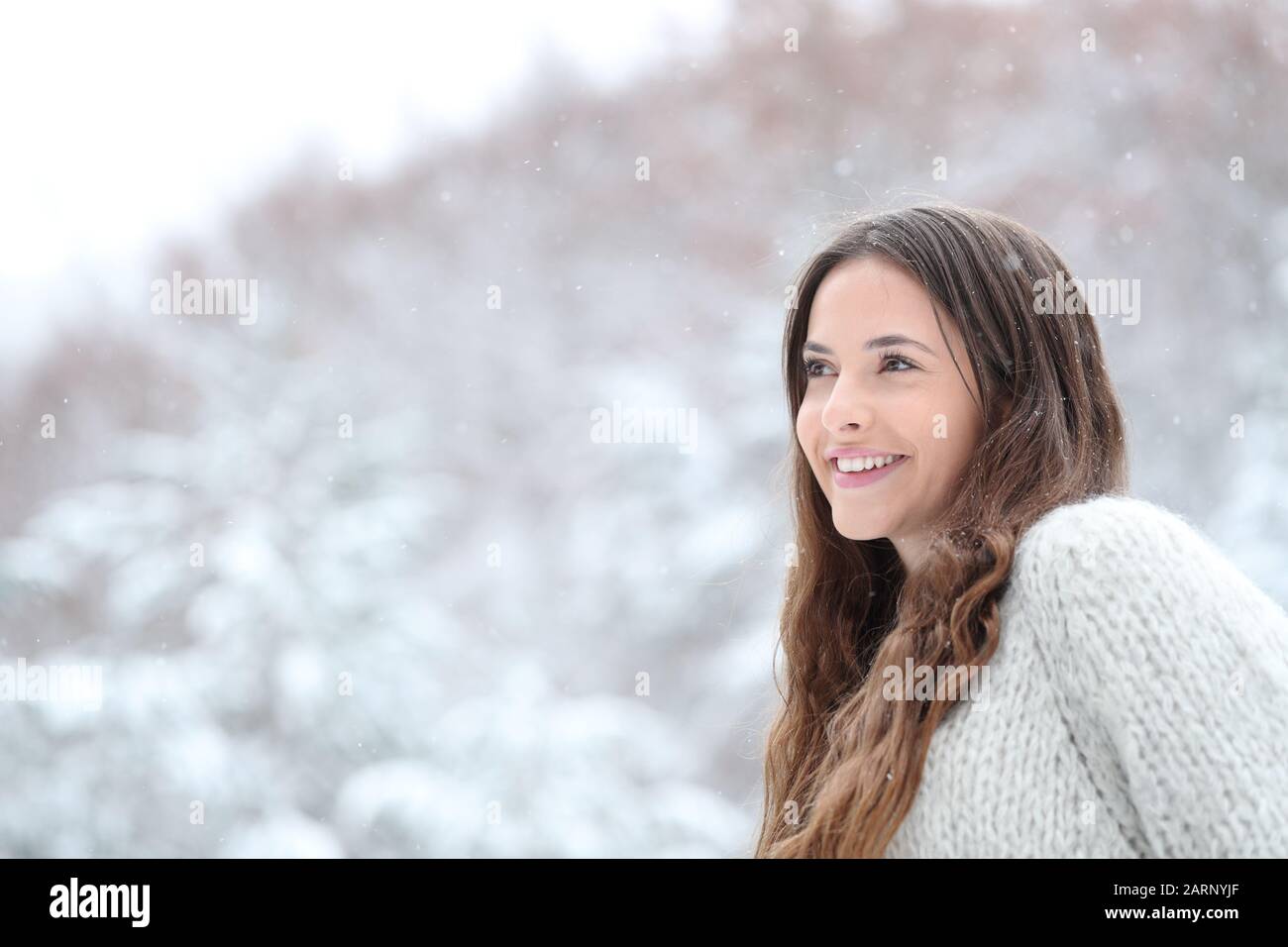 Ragazza felice guardando neve caduta in montagna nelle vacanze invernali Foto Stock