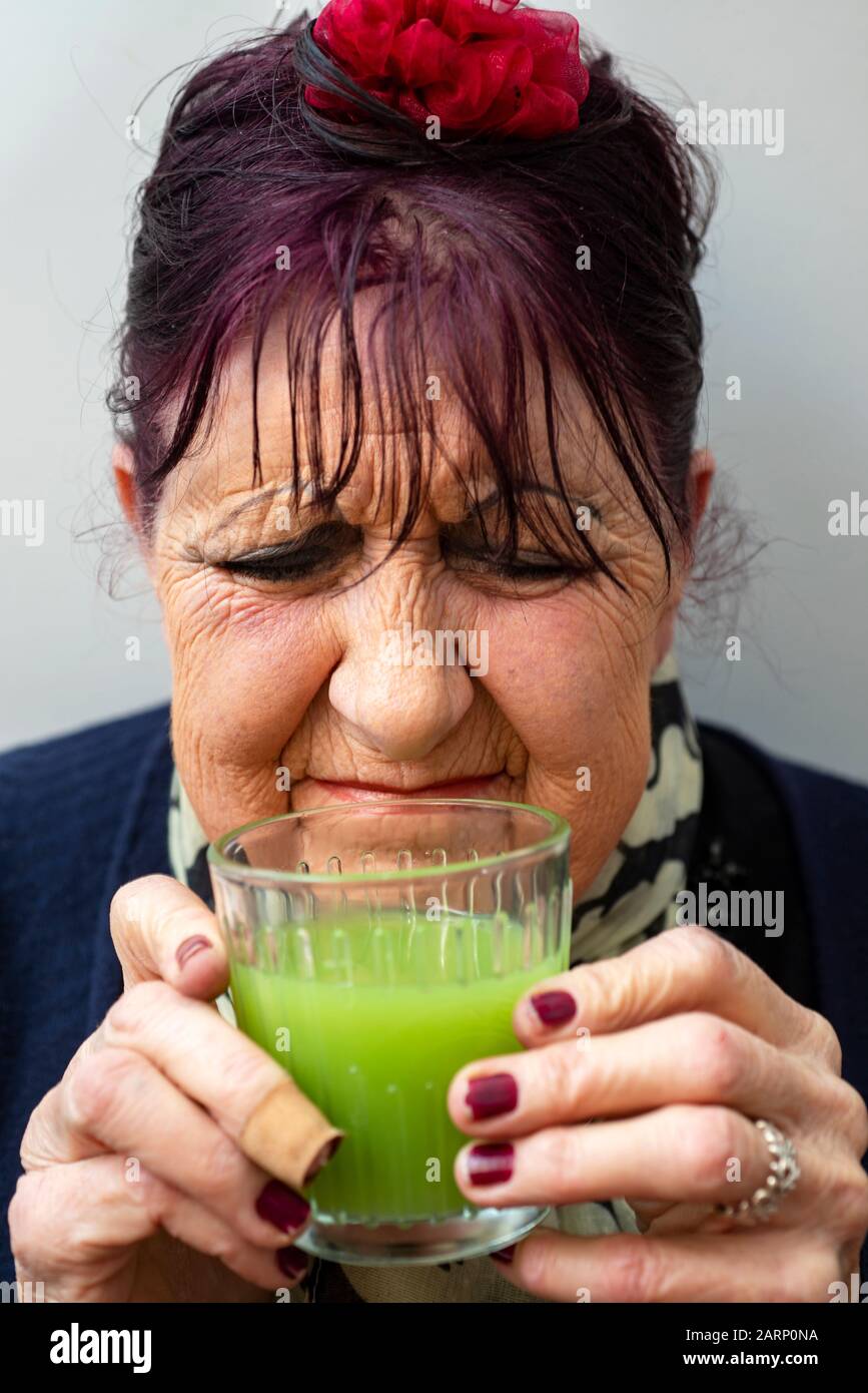 Donna anziana non gradisce una bevanda di succo vegetale organico Foto Stock