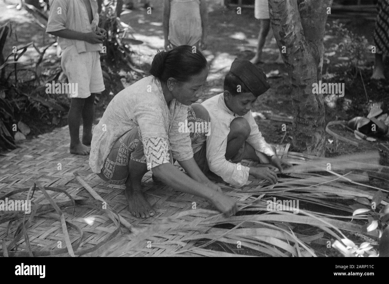 Registrazioni immagini di Indian Life Street. Donna e ragazzo intrecciare uno schermo di Aatap foglie Data: 24 agosto 1948 luogo: Indonesia, Indie orientali olandesi Foto Stock