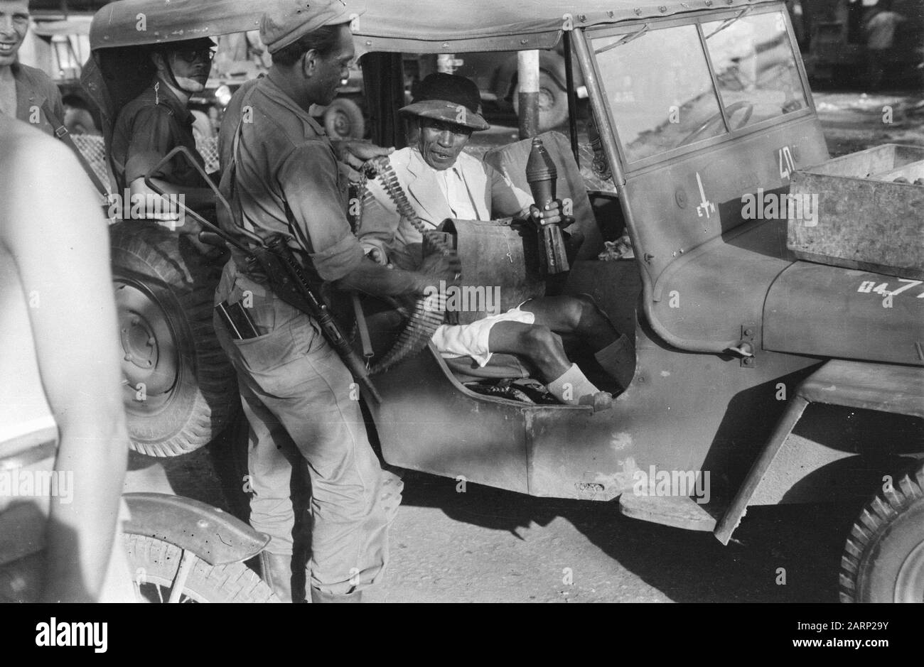 [Uno (arrestato o arrestato?) l'uomo indonesiano in jeep tiene la granata del mortaio e ottiene un nastro modellato. Al suo giro una valigetta.] Annotation: DJK Date: 1947/07/01 Location: Indonesia, Dutch East Indies Foto Stock