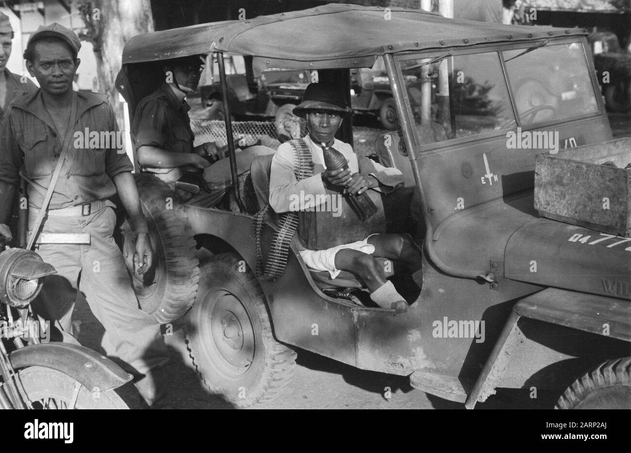 [Uno (arrestato o arrestato?) l'uomo indonesiano in jeep tiene la granata del mortaio ed ha una fascia di modello sopra la sua spalla. Al suo giro una valigetta.] Annotation: DJK Date: 1947/07/01 Location: Indonesia, Dutch East Indies Foto Stock
