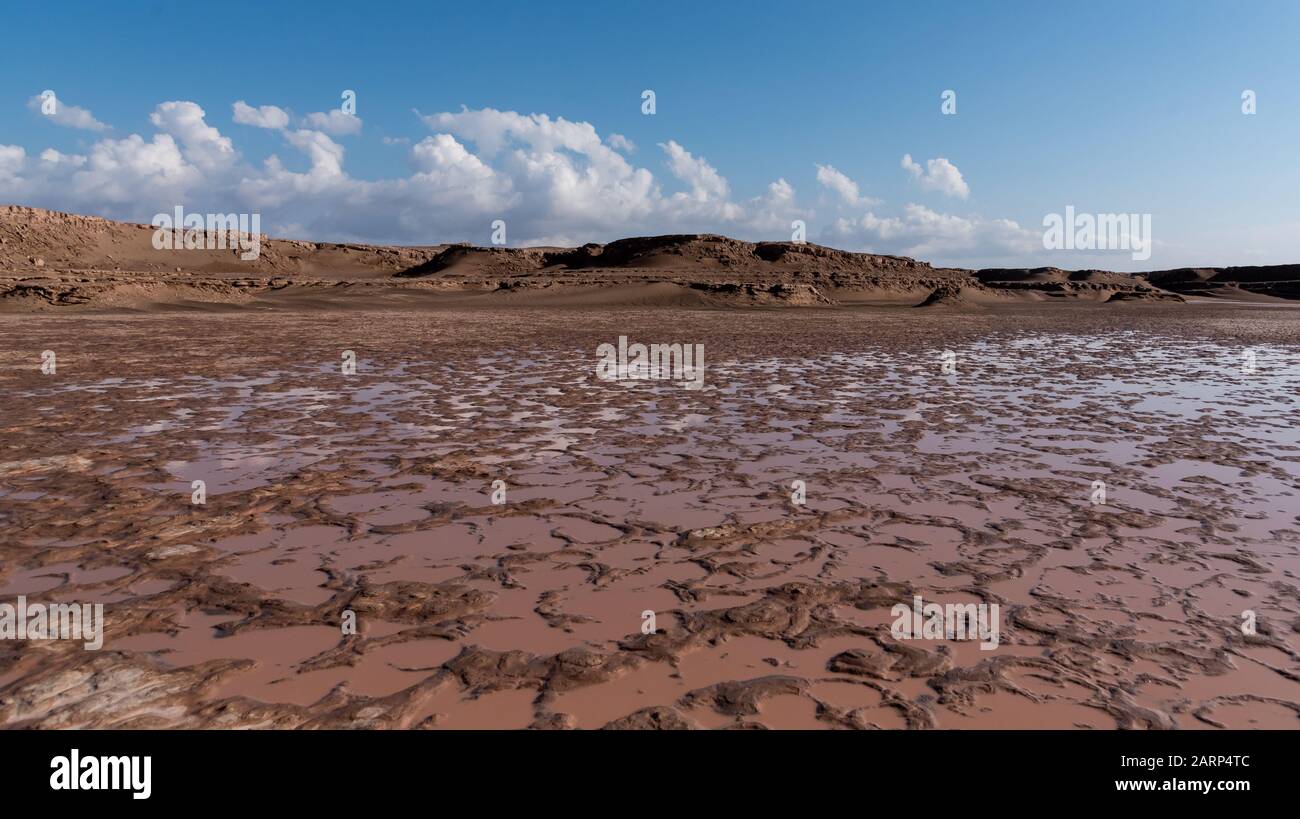 acqua raccolta in un arido dasht e lut o deserto del sahara con cielo nuvoloso e kalut o rocce di sabbia Foto Stock