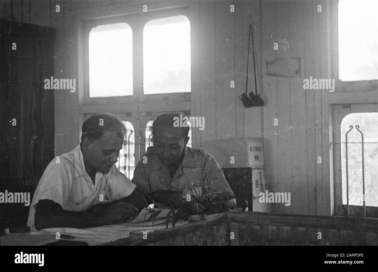 Due uomini, uno in unform piegandosi sopra le carte, seduti in un edificio locale di legno. Dietro Di Loro Pacchetti Data: 1947/01/01 Luogo: Indonesia, Indie Orientali Olandesi Foto Stock Due uomini, uno in unform piegandosi sopra le carte, seduti in un edificio locale di legno. Dietro Di Loro Pacchetti Data: 1947/01/01 Luogo: Indonesia, Indie Orientali Olandesi Foto Stock
