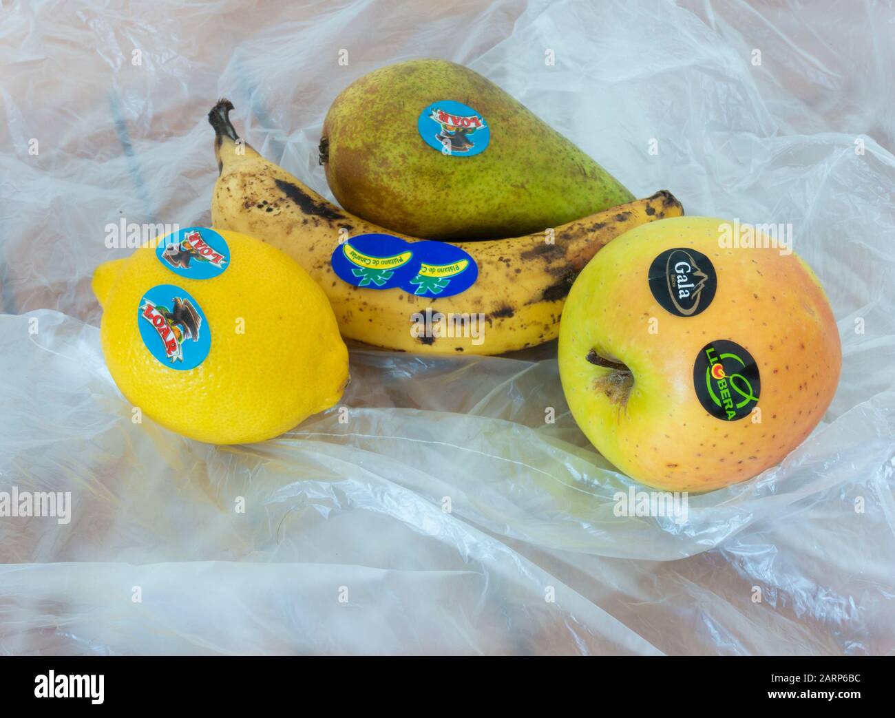 Adesivi in plastica sulla frutta del supermercato su fondo di sacchetti di plastica sottili. Foto Stock