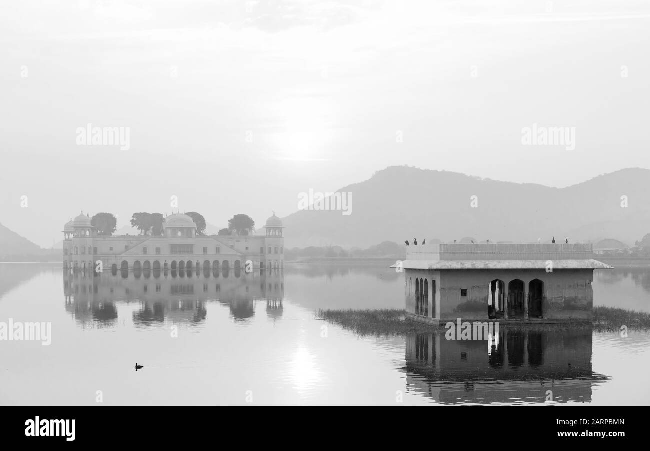 Palazzo reale vuoto circondato da lago e colline di Aravalli come sfondo all'alba a Jaipur, Rajasthan, India. Foto Stock