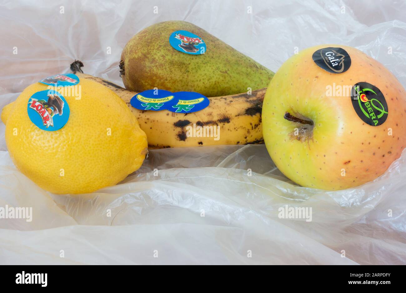 Adesivi in plastica sulla frutta del supermercato su fondo di sacchetti di plastica sottili. Foto Stock