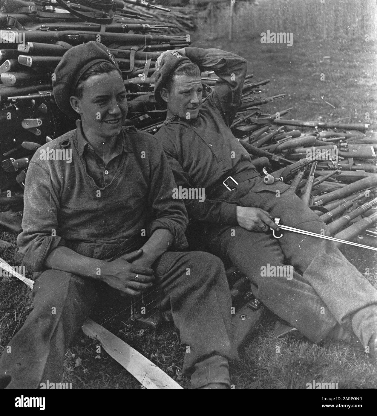 Capitolazione: Soest Due soldati della Polar Bear Division siedono nel deposito di armi a Soest su un enorme mucchio di armi arrese Data: 10 maggio 1945 luogo: Soest, Utrecht (provincia) Parole Chiave: Militare, armi Nome personale: Polar Bear Division Foto Stock