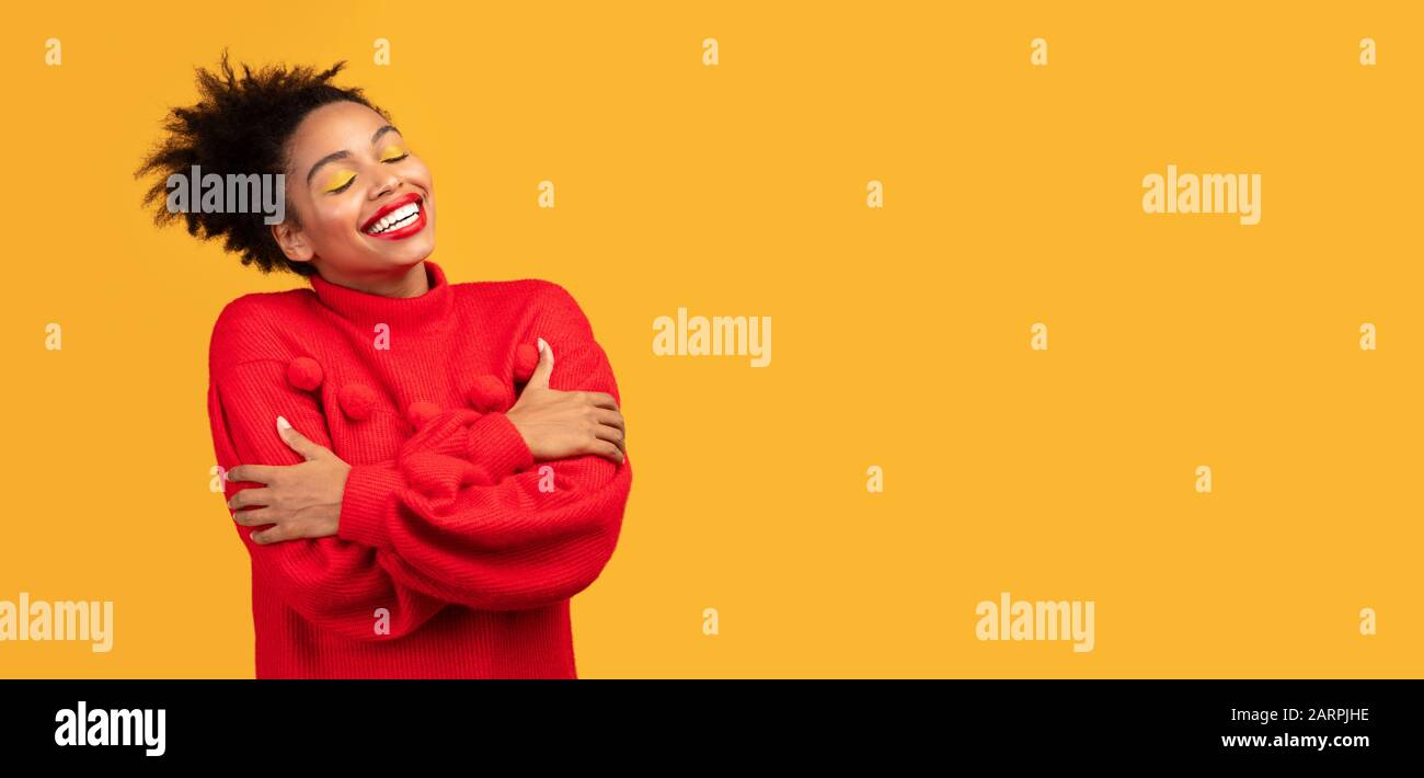 Bella donna afro sorridente abbracciarsi in studio Foto Stock