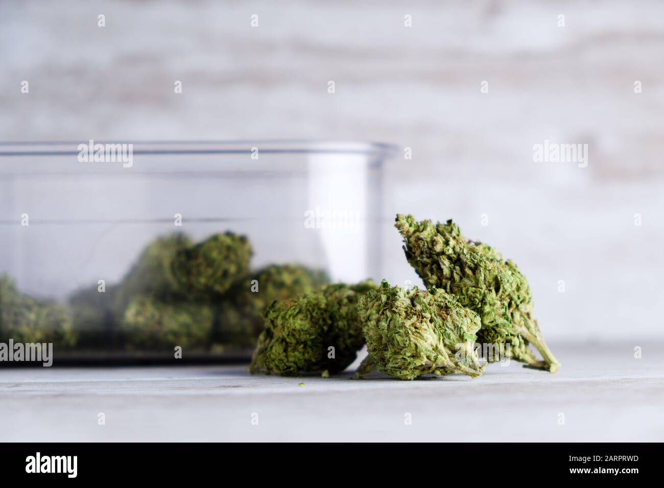 Un contenitore sigillato ad aria e gemme di fiori di marijuana ricreativa contro uno sfondo di pietra bianca dopo che l'Illinois passa una legge per legalizzare le vendite di alghe Foto Stock