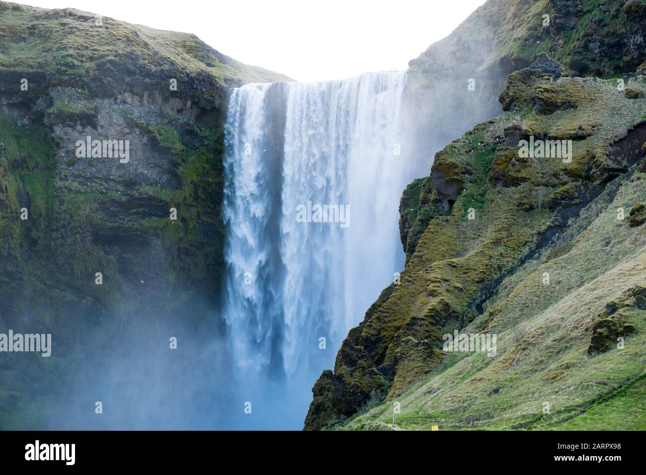 Cascata di Skógafoss che scorre con grande potenza in una giornata torbida in Islanda appena fuori dalla famosa circonvallazione. La cascata è uno dei luoghi più incredibili Foto Stock
