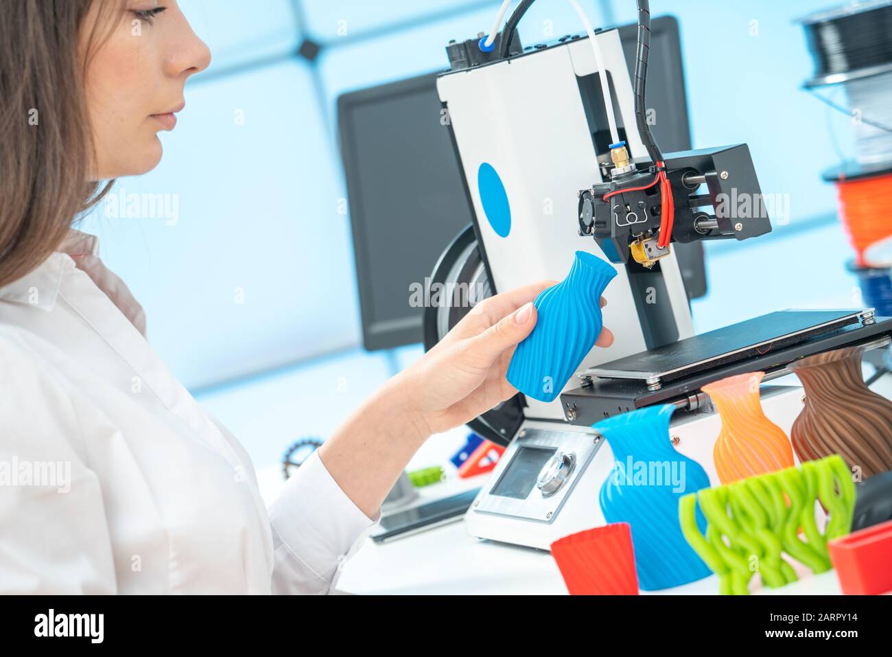 Giovane designer femminile lavora con una stampante 3D in uno studio di design Foto Stock