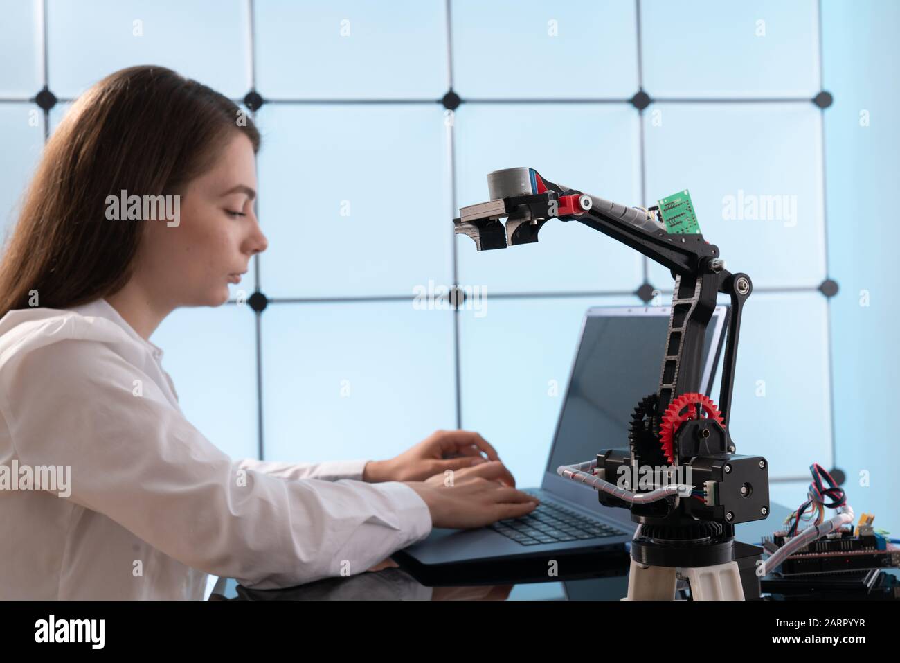 Una giovane donna scrive un algoritmo per il braccio del robot. La scienza laboratorio di ricerca per il braccio robotico modello. Laboratorio di Computer Foto Stock