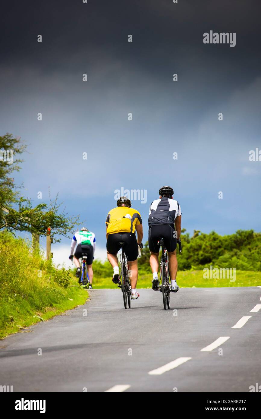I ciclisti su una ripida collina con una tempesta di avvicinamento. Foto Stock