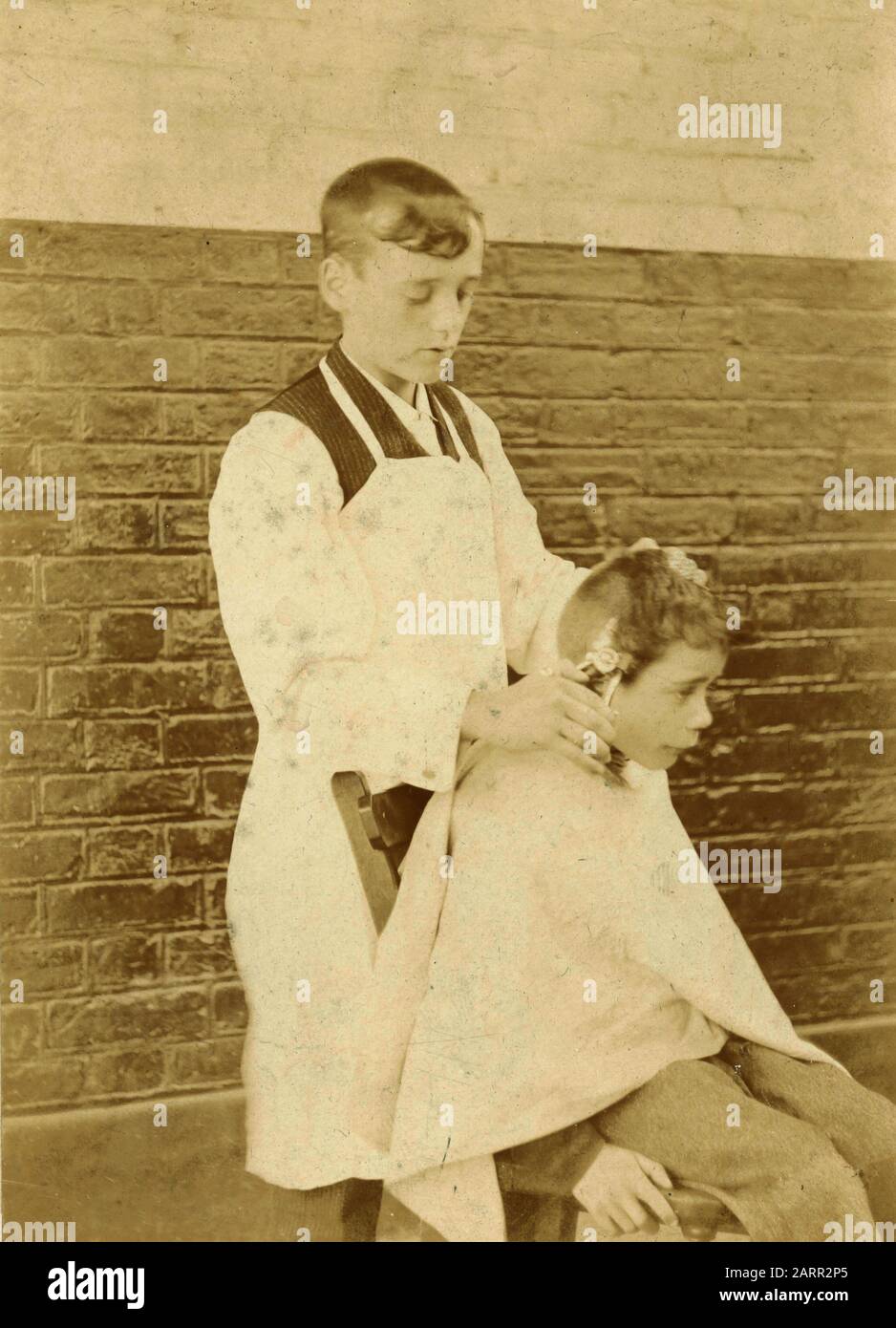 Teenager che taglia i capelli di un bambino, Regno Unito 1890s Foto Stock
